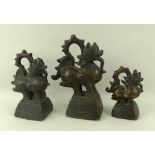 A set of three bronze Burmese opium weights, each in the form of a lion with dangling tongue,