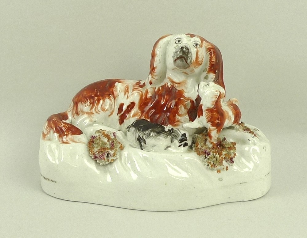 A 19th century Staffordshire model of a King Charles spaniel with two puppies, 12 by 6 by 8cm.