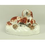 A 19th century Staffordshire model of a King Charles spaniel with two puppies, 12 by 6 by 8cm.