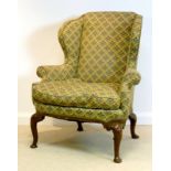 A George I style walnut framed wing back armchair, circa 1900, with scroll over arms,