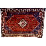A Shiraz rug with orange red ground, central cream diamond medallion with latchhook decoration,