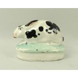 A Staffordshire model of a rabbit, 19th century, on oval base, hand painted black and white,