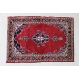 An Iranian rug with open red ground, central dark blue medallion with pendants,