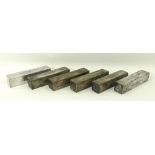 A group of six white metal knife rests of rectangular block form,