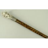 A simulated snakewood walking stick, the antler top carved with a hand holding a skull, 95cm.