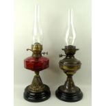 A Victorian oil lamp with cranberry glass reservoir, 56cm, and another similar in brass, 54cm,