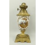 A ceramic and brass oil lamp, the ceramic body with hand painted reserves of musicians and flowers,