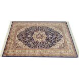 A Keshan rug with dark blue ground, central cream medallion, dense field with scrolling decoration,