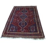 A Persian rug with red ground, mid 20th century, with three dark blue medallions,