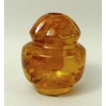 An amber ball with inclusions, carved in the shape of a lidded urn, with drilled recess, 4cm high.