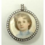 An Edwardian miniature of a young boy in a circular silver and seed pearl mount with pendant loop,