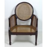 A caned bergere armchair, early 20th century, with a circular back,