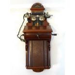 An early 20th century wall mounted telephone, on walnut case with cradle, slope and hook,
