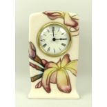 A Moorcroft mantel clock, in magnolia pattern, the circular face with Arabic numerals,