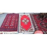 Three Bokhara style red rugs.