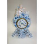 A French porcelain mantel clock, early 20th century, surmounted with a cherubic figure and a dove,