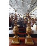 A pair of giltwood and metal worked table lamps with "palm tree" carved bodies on square bases,