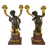 A pair of bronze and ormolu putto candlesticks on red marble plinths, 42cm high.