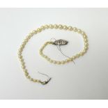 A single row necklace of graduated cultured pearls, on a diamond set marquise shaped cluster clasp,