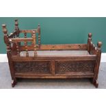 A 17th century carved oak cradle on turned supports, 100cm wide.