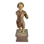 A late 17th century polychrome painted carved wooden figure depicting a young boy on a wooden