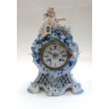 A French porcelain mantel clock, early 20th century, surmounted with a cherubic figure and a dove,