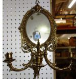 A gilt brass oval wall mirror with sconces.