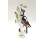 A Meissen porcelain great spotted woodpecker, early 20th century, modelled on a leafy branch,