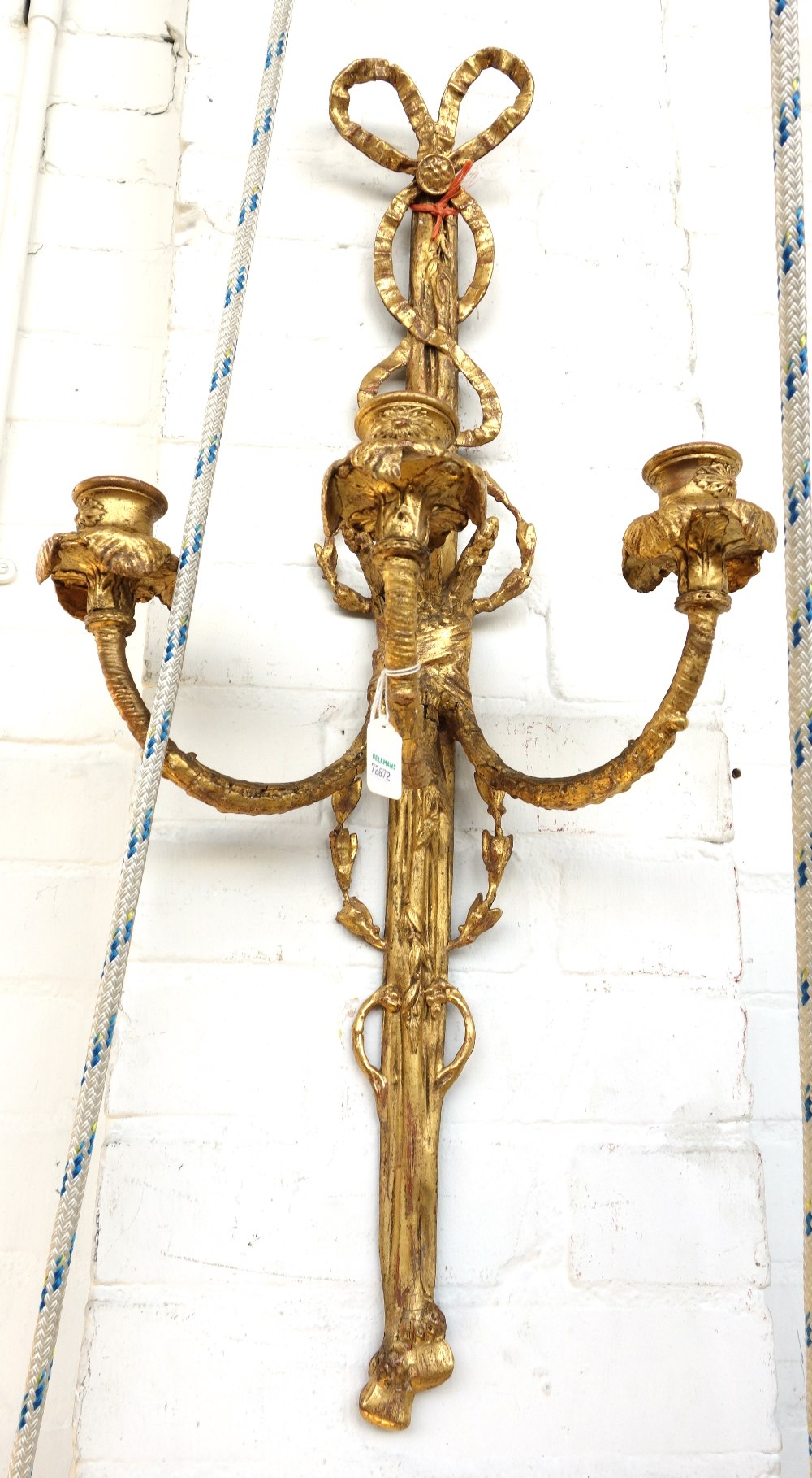 A pair of gilt three branch wall lights, with triple candle branches,