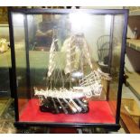 A 20th century Oriental white metal model of a boat in an ebonised glazed case.