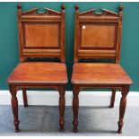 A pair of Victorian mahogany hall chairs, with broken architectural crest,