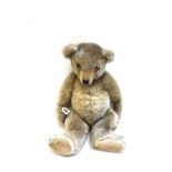 A golden haired teddy bear, 20th century, with orange glass eyes, hand stitched snout,