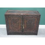 A late 19th century Chinese hardwood two door low cupboard with extensive carved decoration,