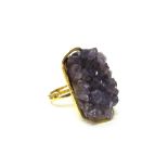 A gold ring, claw set with a piece of natural amethyst crystal,