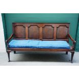 A George III mahogany banded oak settle, with four panel back and open arms, on club supports,