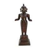 An Indian bronze figure of Krishna, 19th century, with inset ivory eyes and traces of red paint,