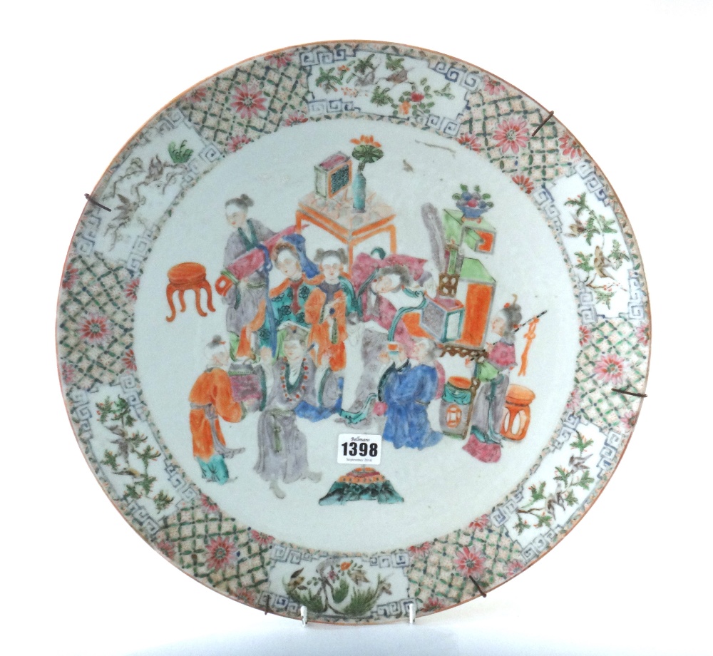 A Chinese famille-rose circular dish, circa 1900, painted with figures at leisure amongst tables,