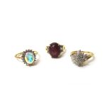 A 9ct gold ring, claw set with an oval cabochon ruby, between diamond set two stone shoulders,