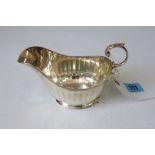 A silver helmet shape sauce boat and a silver Georgian pattern three piece condiment set,