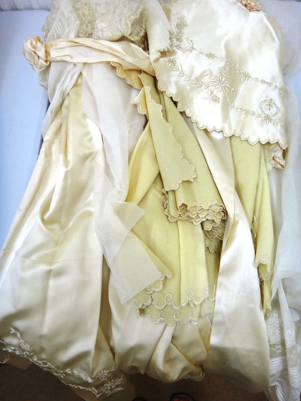 A child's cream satin robe, embroidered with raised floral garlands, together with a matching cape,