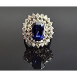 A sapphire and diamond cluster ring, claw set with the cushion shaped sapphire at the centre,