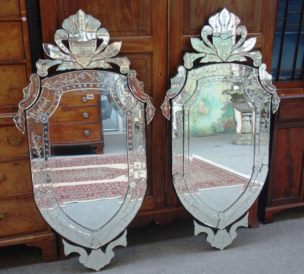 A pair of 20th century cut and etched Venetian glass wall mirrors, each of shield shape outline,