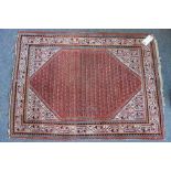 A Saraband rug, Persian, the madder field filled with botehs, ivory spandrels and matching border,