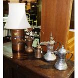 A group of four Turkish metal jugs and a cylindrical copper table lamp.