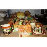 A quantity of ceramic cottages and similar tea pots and sugar bowls including Beswick and others.