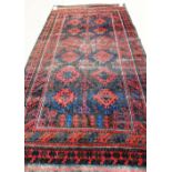 A Beluchistan carpet, the brown field with a stylised tree bearing pairs of madder rosettes,