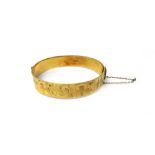 A 9ct gold oval hinged bangle, the front with feathered scroll engraved decoration, on a snap clasp,