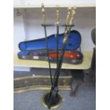 A set of ebonised metal fire tools and stand with brass handles (shovel 74cm),