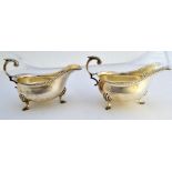 A pair of silver sauceboats, each with a scrolling handle,