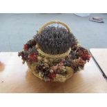 A two tier wicker basket of circular form decorated with an arrangement of dried flowers and